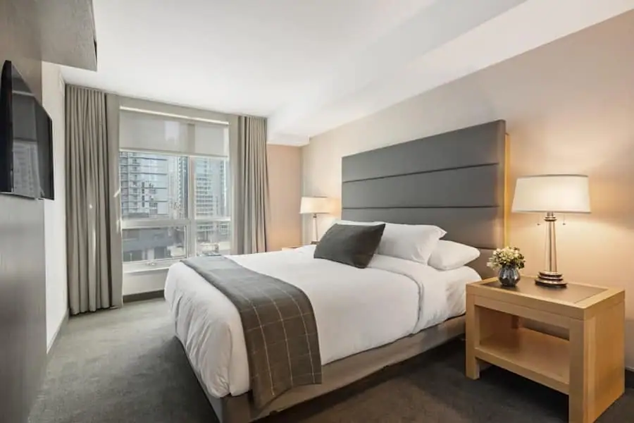 Neatly made bed with layered bedding in soft natural light